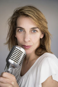 Portrait of woman singing song against colored background