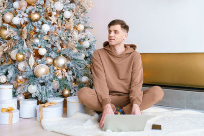 Caucasian man working on winter holidays in living room sitting on floor near