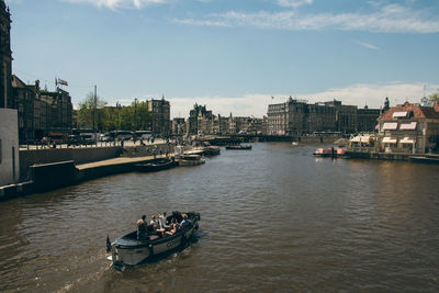 Boats in river by city against sky