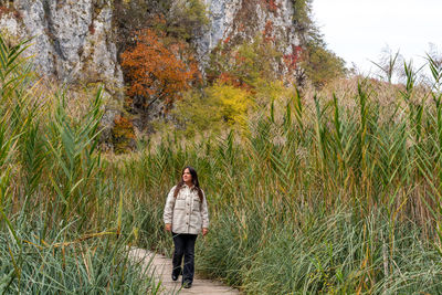 Young woman walking on wooden path surrounded by reed in plitvice lakes national park in croatia