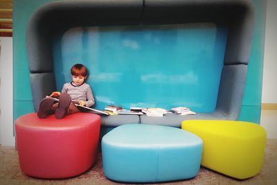 Boy reading book while sitting in furniture