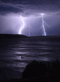 Lightning over sea against sky at night