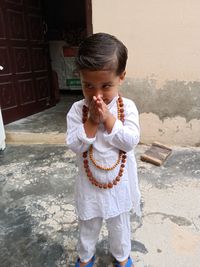 Cute girl in traditional clothing praying while standing on land