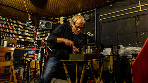 50-year-old man trying to repair old amplifier with great effort