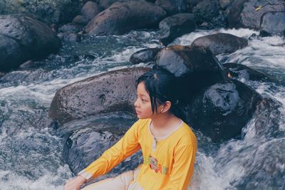 Full length of boy standing on rock in sea