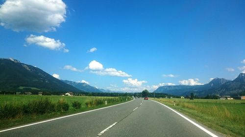 Road passing through landscape against blue sky