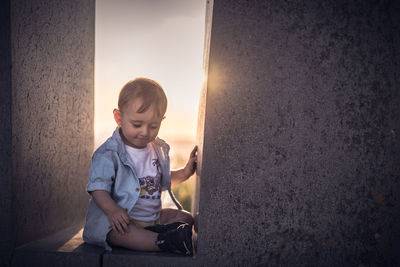 Cute boy sitting on wall at home