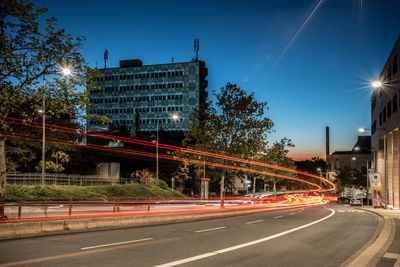 Light trails on street in city against sky