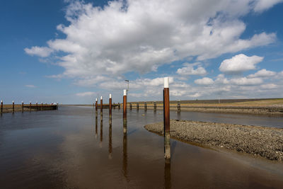 Wooden posts in sea against sky