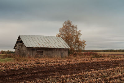 An old barn house standing by the plowed field on a grey autumn day at the rural finland. 