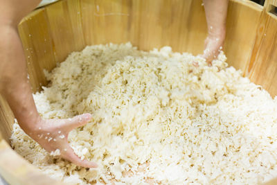 High angle view of worker mixing mozzarella cheese in wooden container at factory