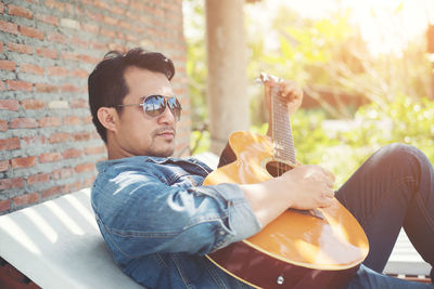 Man playing guitar while relaxing outdoors