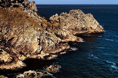 Rock formation in sea against sky