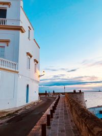 People on footpath by sea against sky