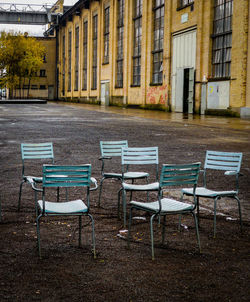 Empty chairs and tables at sidewalk cafe by buildings in city