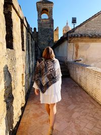 Rear view of woman walking by old building