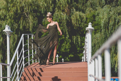 Woman standing by railing against trees