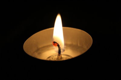 Close-up of lit tea light in darkroom