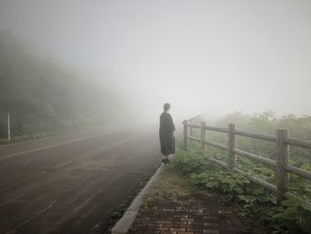 Rear view of man walking on road against sky