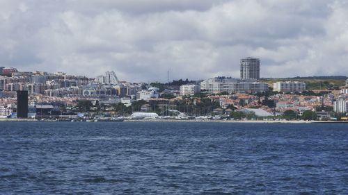 Sea by cityscape against sky