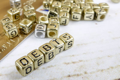 Close-up of debt text made with golden toy blocks on table