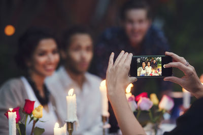 Cropped image of woman photographing friends at garden party