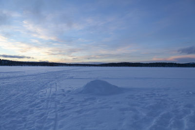 Scenic view of snowcapped field against sky during sunset