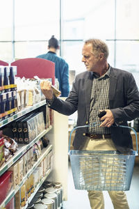 Mature man reading label on food package in supermarket