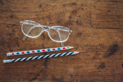 Directly above view of pencils and eyeglasses on wooden table