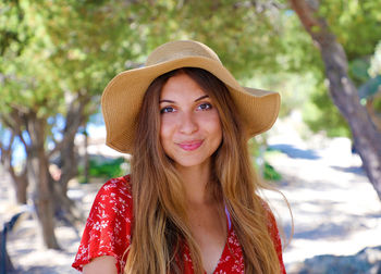 Portrait of smiling young woman wearing hat while standing on land