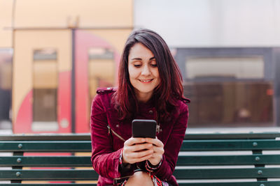 Woman using mobile phone sitting on bench