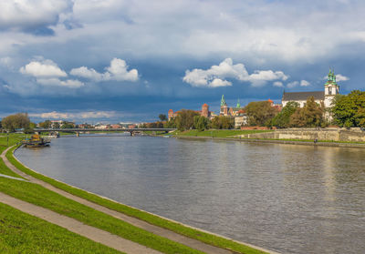 View of river and buildings against cloudy sky