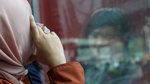 Rear view of woman wearing hijab looking through window