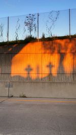 Shadows on a wall of crosses at sunset