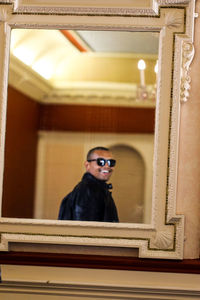 Man wearing sunglasses reflecting on mirror