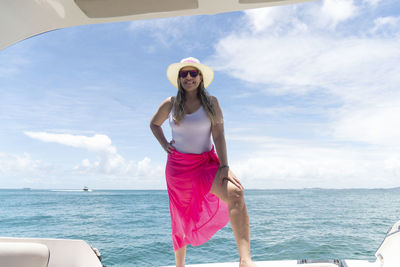 A woman on top of a boat against the sea in the background. 