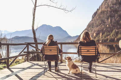 Friends sitting by lake against mountains