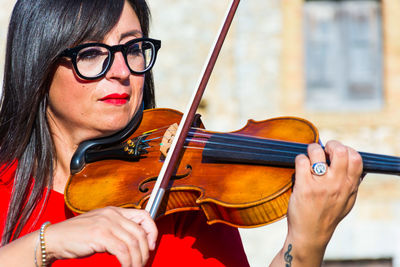 Close-up of woman playing violin in city