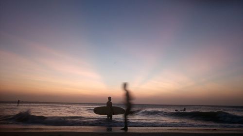 Silhouette man on beach against sky during sunset