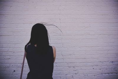 Rear view of woman standing against wall