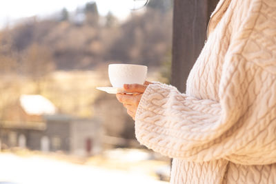 Female hands in a sweater hold a cup of coffee