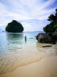 Side view of woman standing in sea against sky