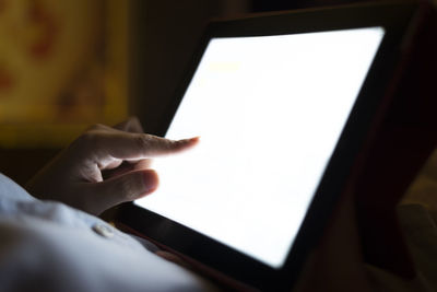 Midsection of person using digital tablet in darkroom