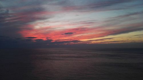 Scenic view of sea against dramatic sky during sunset