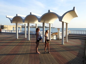 Mother and daughter standing on promenade against sky