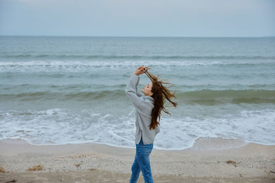 Full length of young woman standing at beach