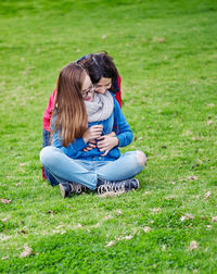 Rear view of woman sitting on grassy field