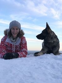 Woman with dog sitting in snow