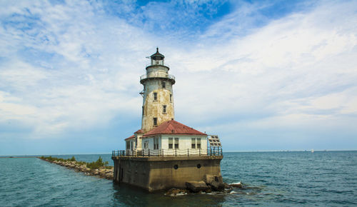 Lighthouse by sea against sky