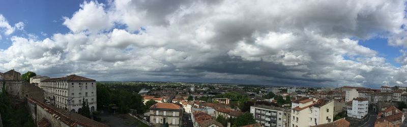 Buildings in town against cloudy sky